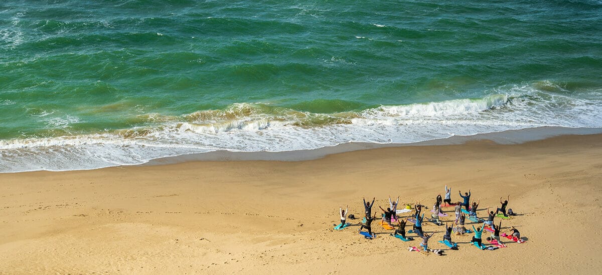 A group of people doing well-being yoga on a beach