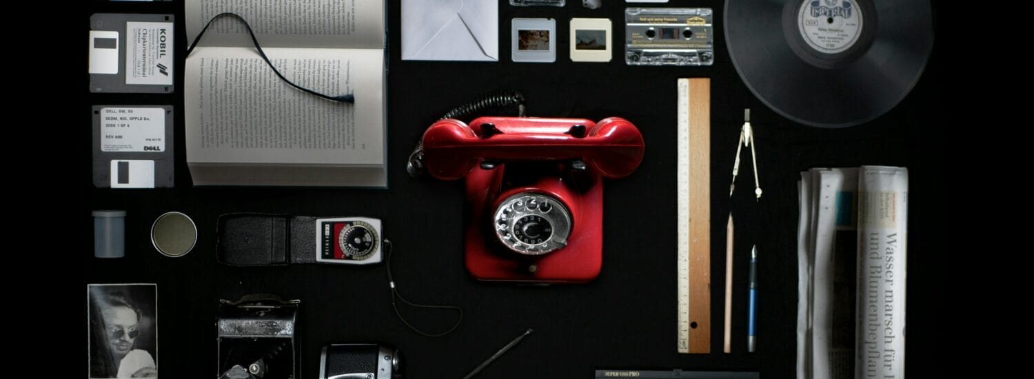 collage of items including a red rotary phone, a vinyl LP, books, and envelopes