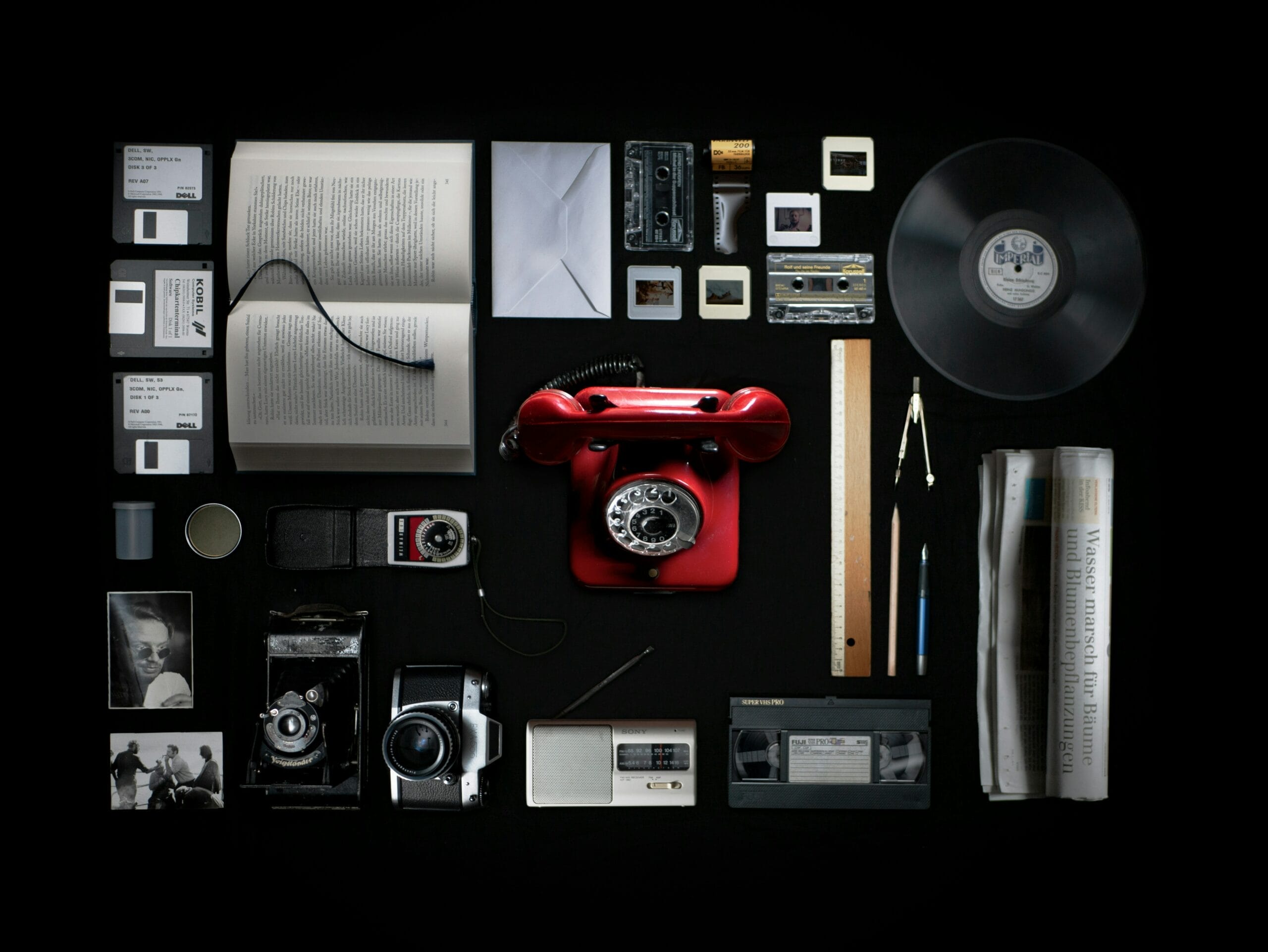 collage of items including a red rotary phone, a vinyl LP, books, and envelopes
