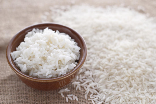 White jasmine rice in a brown bowl and on brown clothe