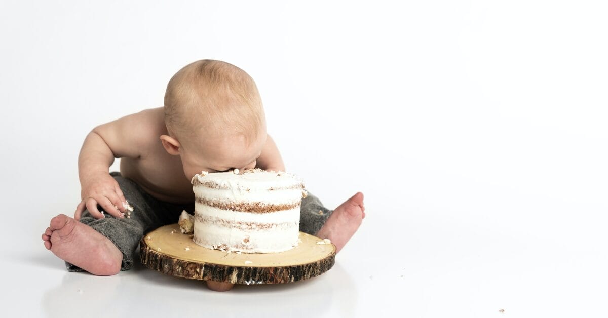 An image of a baby smashing its face into a cake to celebrate the anniversary of "Baby Bust," a book about balancing work and life.