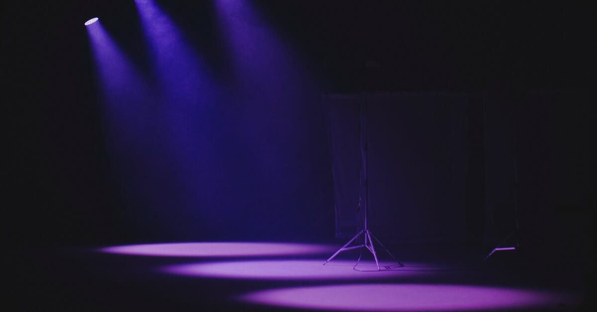 purple lights shine down on a dark stage